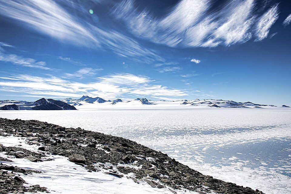The flat blue-ice runway site at Union Glacier, with mountains on the horizon under a clear sky.