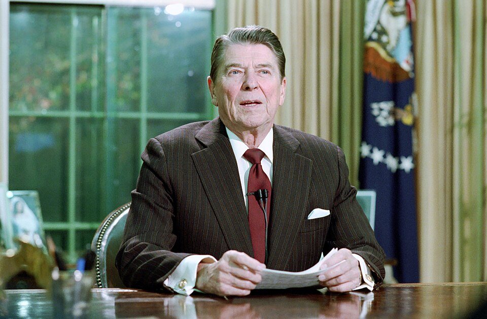 President Reagan at his desk in the Oval Office, speaking to television cameras.