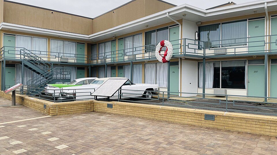 The Lorraine Motel in Memphis: a two-story motel with a long balcony, a wreath hanging on the upper railing and two vintage cars parked below.