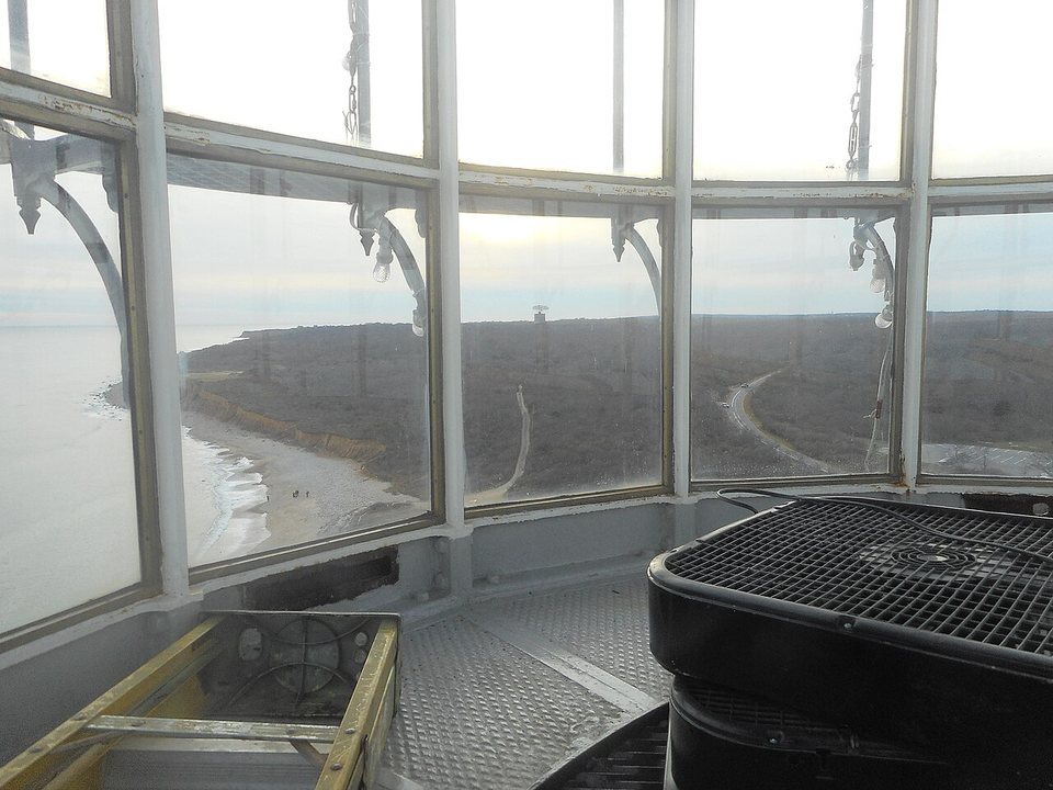 The view through the lantern-room windows of the Montauk Point Lighthouse: the beach and the wooded land of Camp Hero, with the radar tower small in the distance.