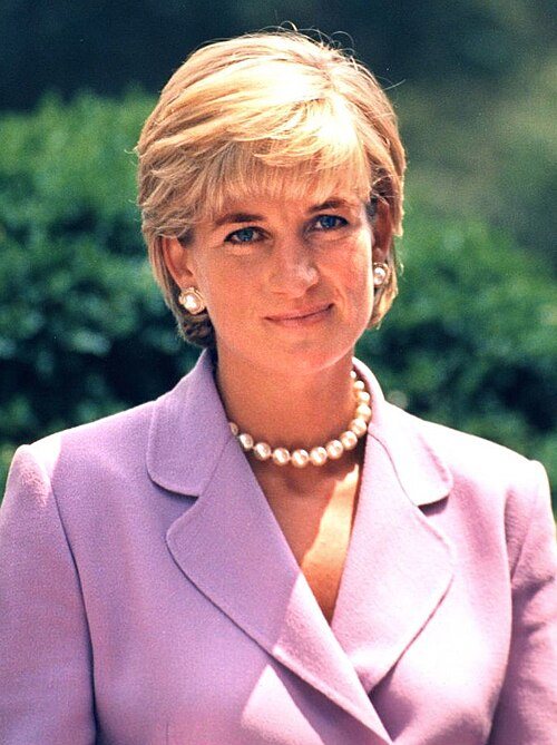 Diana, Princess of Wales, in a pink jacket and pearl necklace, smiling, in a 1997 photo.